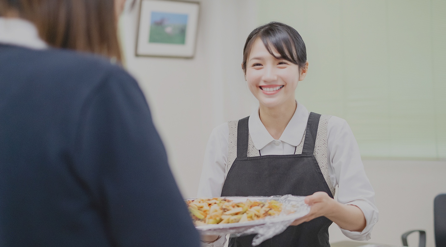 商品を持ち、笑顔で会話する管理栄養士の写真