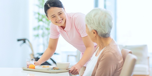 老人の方に料理を届けている女性