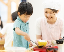 ご飯をよそっている子供と、お椀を持っている女性